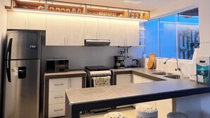 Une cuisine moderne dotée d’appareils électroménagers en acier inoxydable, d’un îlot central et de tabourets de bar.