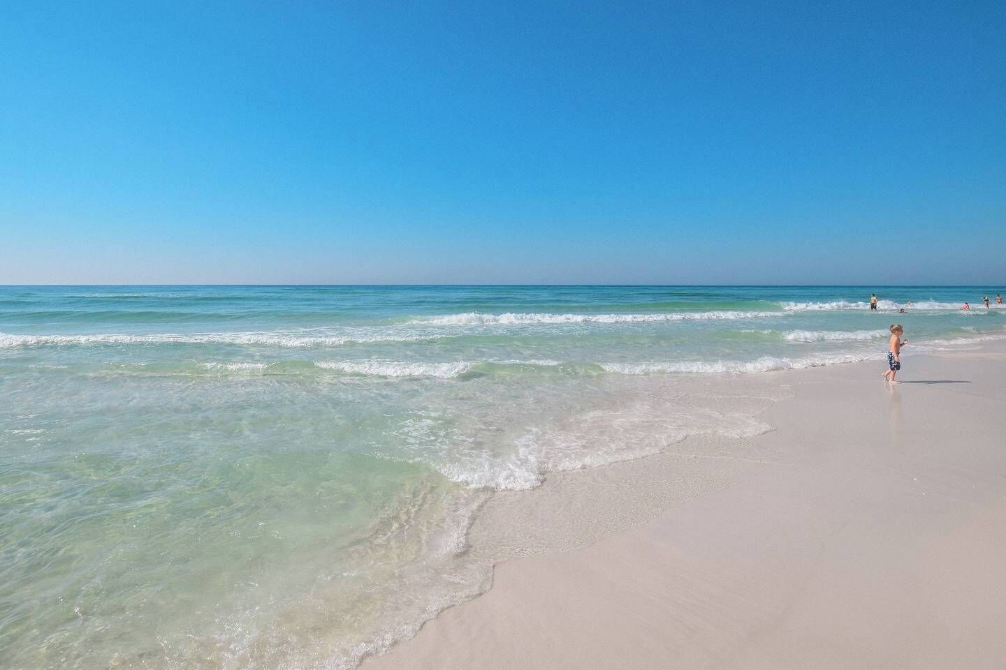 Une plage à l’eau turquoise et limpide, bordée d’un rivage sablonneux.