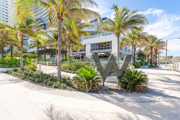 A modern hotel with a large 'W' sign, palm trees, and a paved walkway.