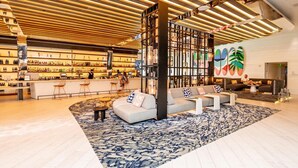 A spacious lobby with a central seating area, a bar with a variety of bottles, and a large, patterned rug.