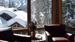 Ein Zimmer mit großen Fenstern, einer Holzbalkendecke und zwei Ledersesseln.