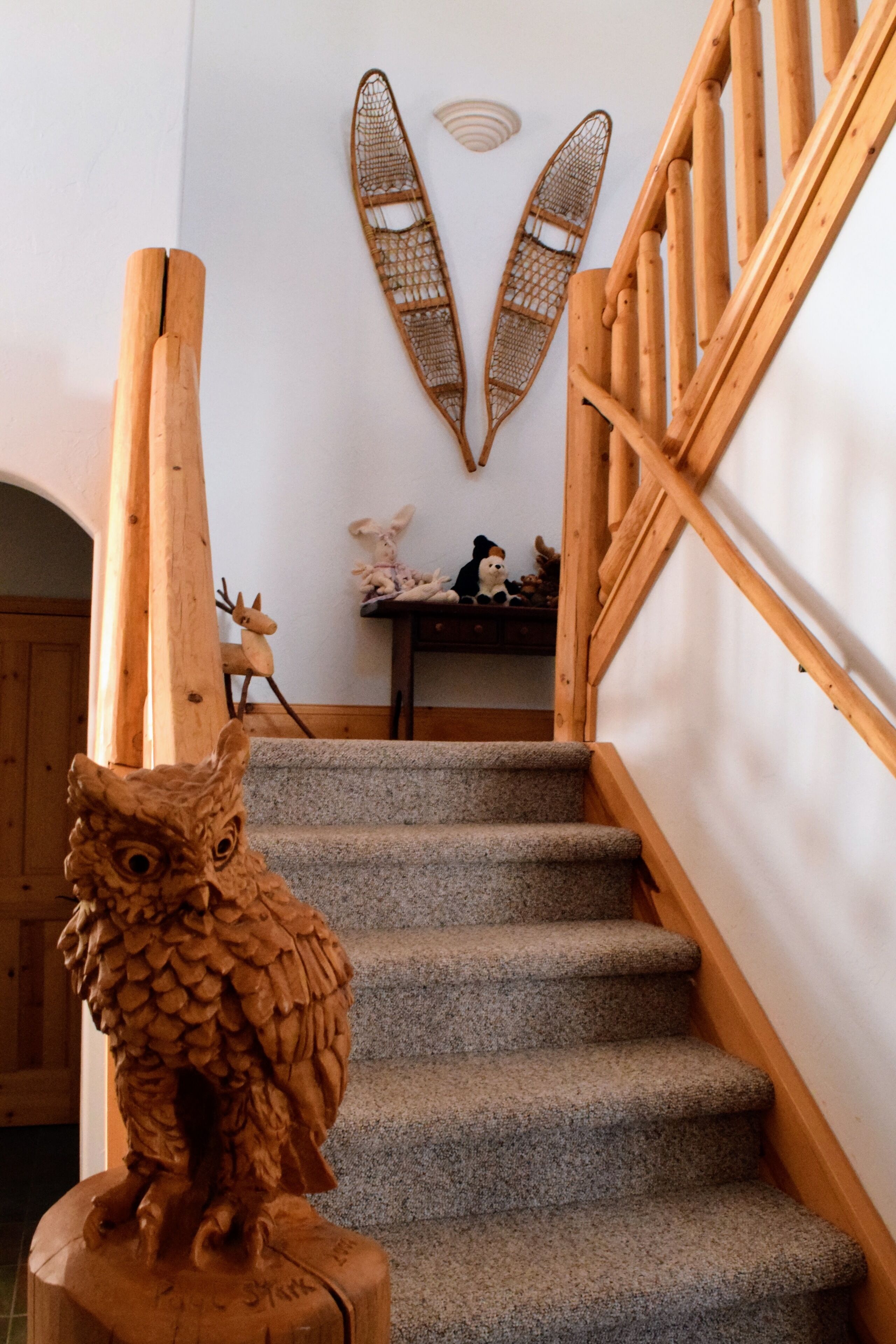 Una escalera de madera con un búho tallado en el escalón inferior.