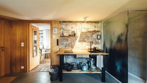 Een compacte keuken met houten wanden, een inbouwspoelbak en een rustieke steenschildering.
