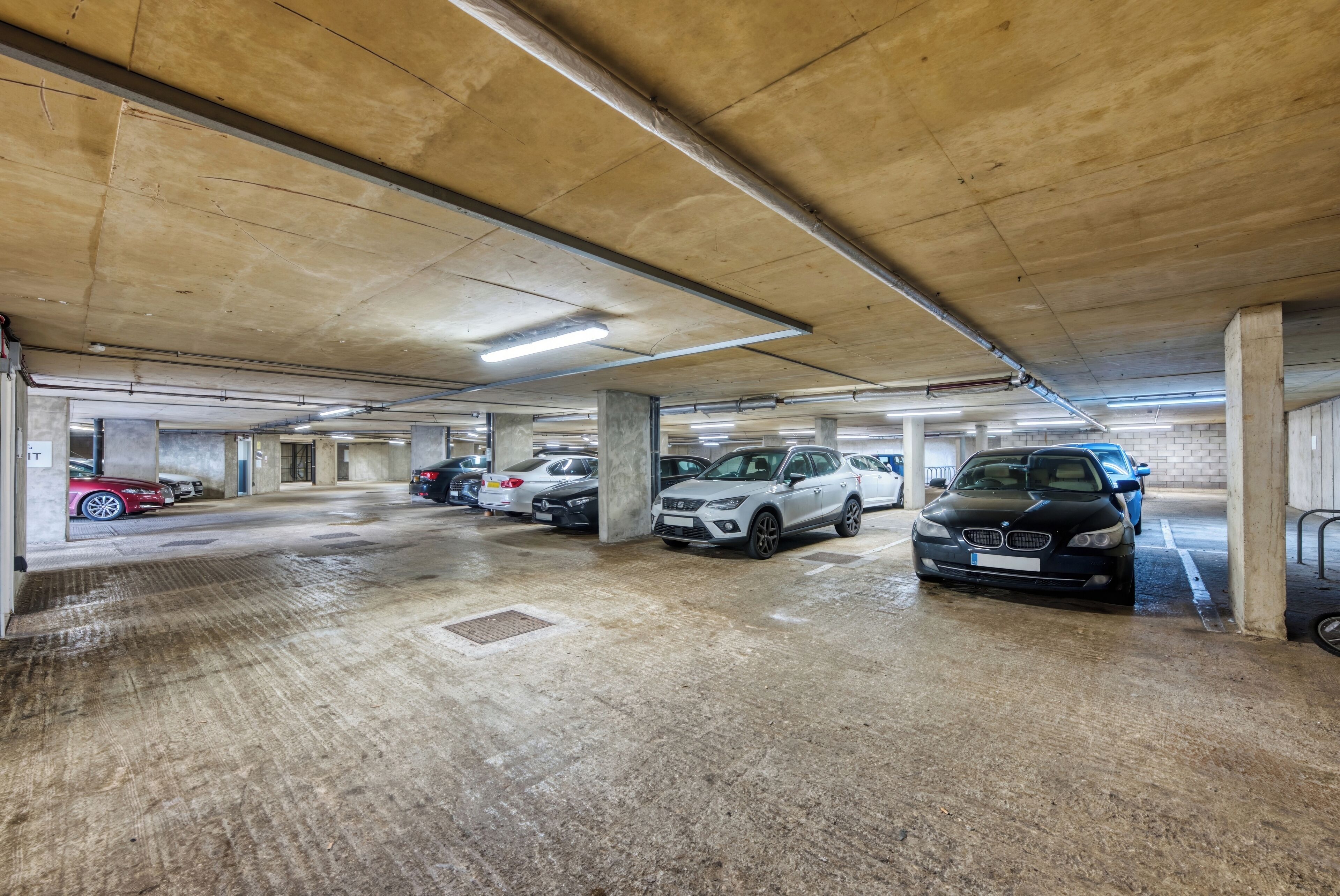 Eine mehrgeschossige Parkgarage mit Betonpfeilern und Neonbeleuchtung.