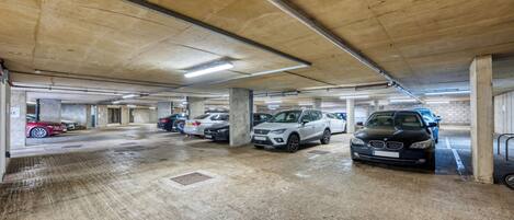 Eine mehrgeschossige Parkgarage mit Betonpfeilern und Neonbeleuchtung.