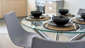 A modern kitchen with a glass dining table set with black bowls and silverware. - The Pinnacle by Cotels (Northampton)