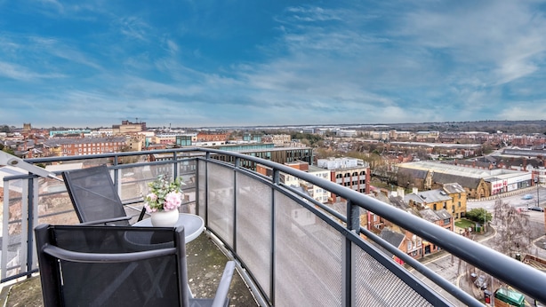 A balcony with a view of a cityscape, including buildings and a clear sky. - The Pinnacle by Cotels (Northampton)