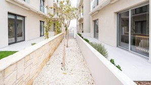 Un edificio moderno con un estrecho sendero bordeado por muros de piedra y vegetación.
