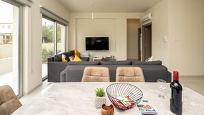 Una sala de estar moderna con sofá, sillas, una mesa de comedor y televisor.