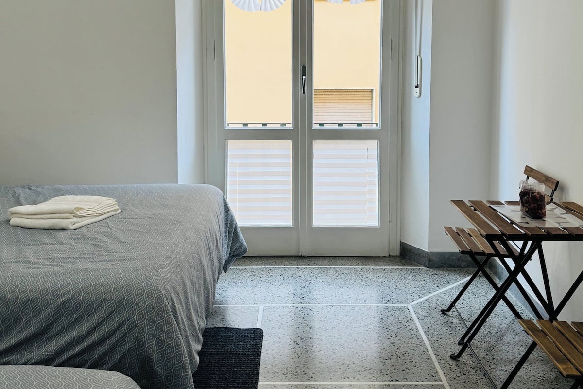 Une chambre d’hôtel avec un lit, une petite table et une chaise, ainsi qu’une porte avec une fenêtre.