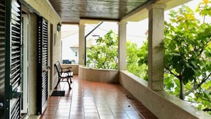 Un balcon abrité avec un sol carrelé, une chaise et une petite table.