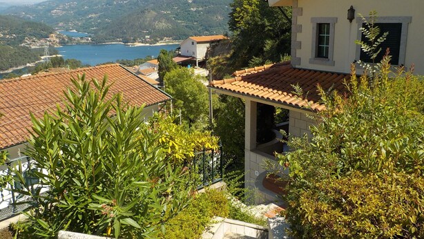Une villa côtière avec des toits en tuiles de terre cuite, un escalier en pierre et une végétation luxuriante.