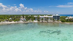 A coastal hotel with clear turquoise waters, palm trees, and a beach. - VILLA BELLAMAR AKUMAL (Akumal)