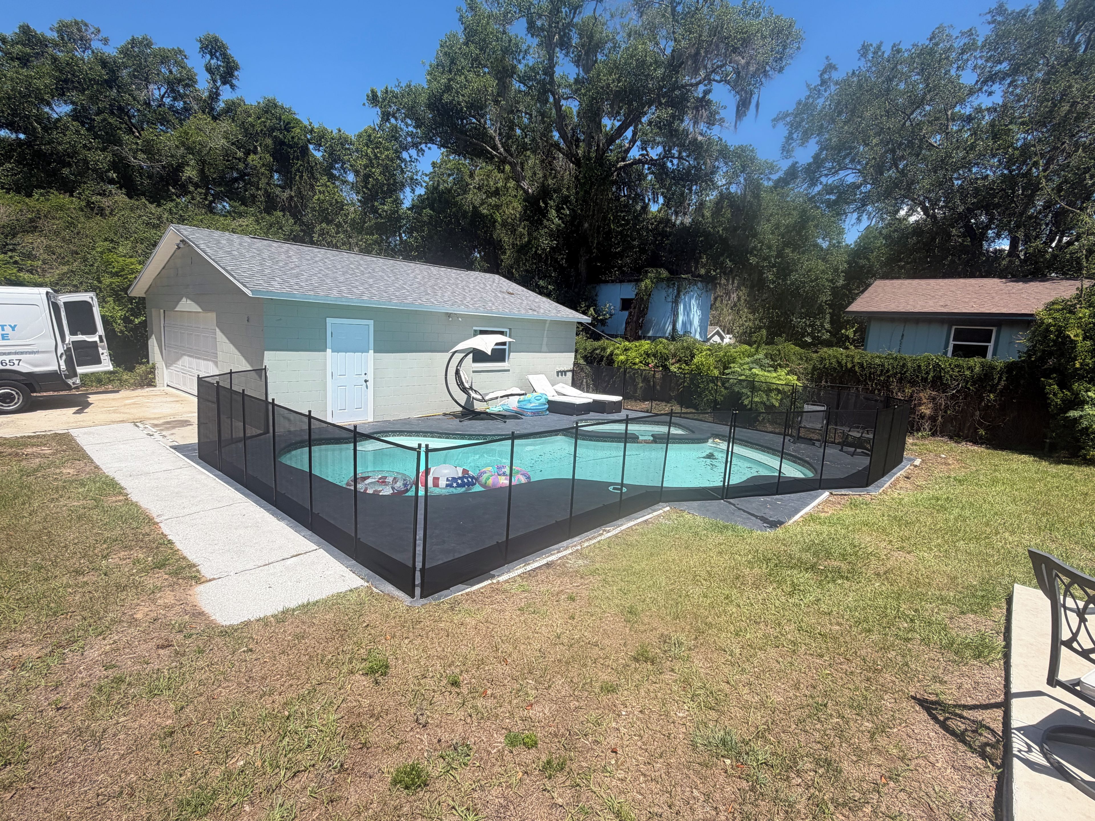 A residential backyard with a swimming pool, a small house, and a truck.
