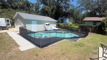 A residential backyard with a swimming pool, a small house, and a truck.