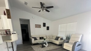 A modern living room with a sectional sofa, a coffee table, and a ceiling fan.