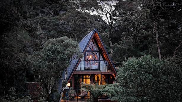 Une cabane dotée d’un toit en pente, entourée d’une forêt dense.