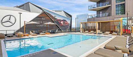 Una piscina con sillones de descanso, el logotipo de Mercedes-Benz y un edificio con un gran anuncio.