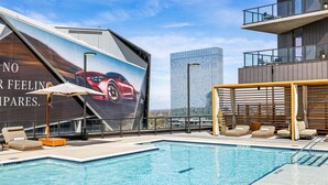 A rooftop pool with lounge chairs, a large advertisement, and a cityscape view. - Hotel Phoenix Atlanta (Atlanta)