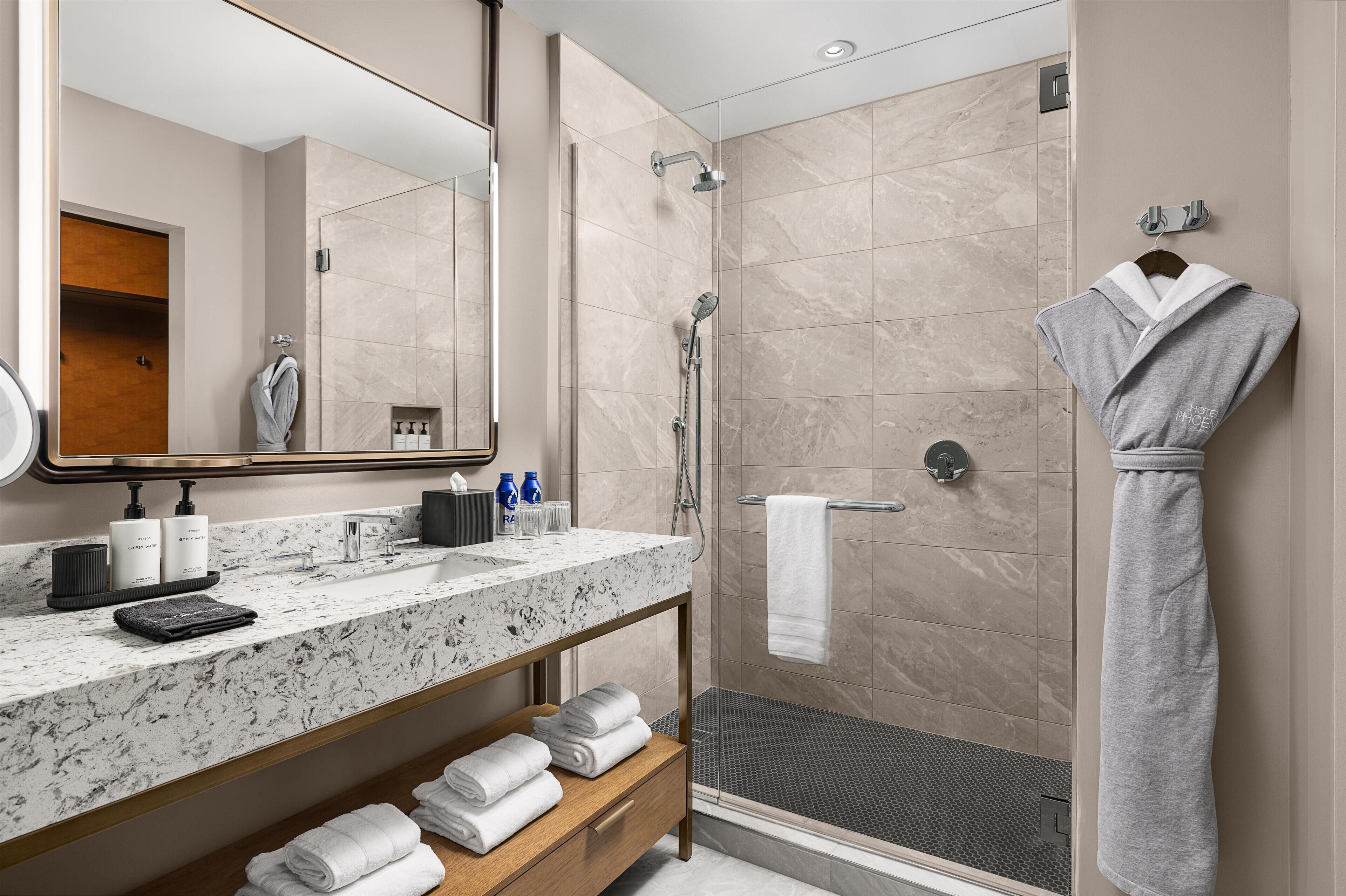 A modern bathroom with a marble sink, a glass-enclosed shower, and neatly folded towels.
