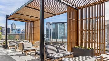 A rooftop terrace with outdoor seating, a wooden pergola, and a view of the city skyline.