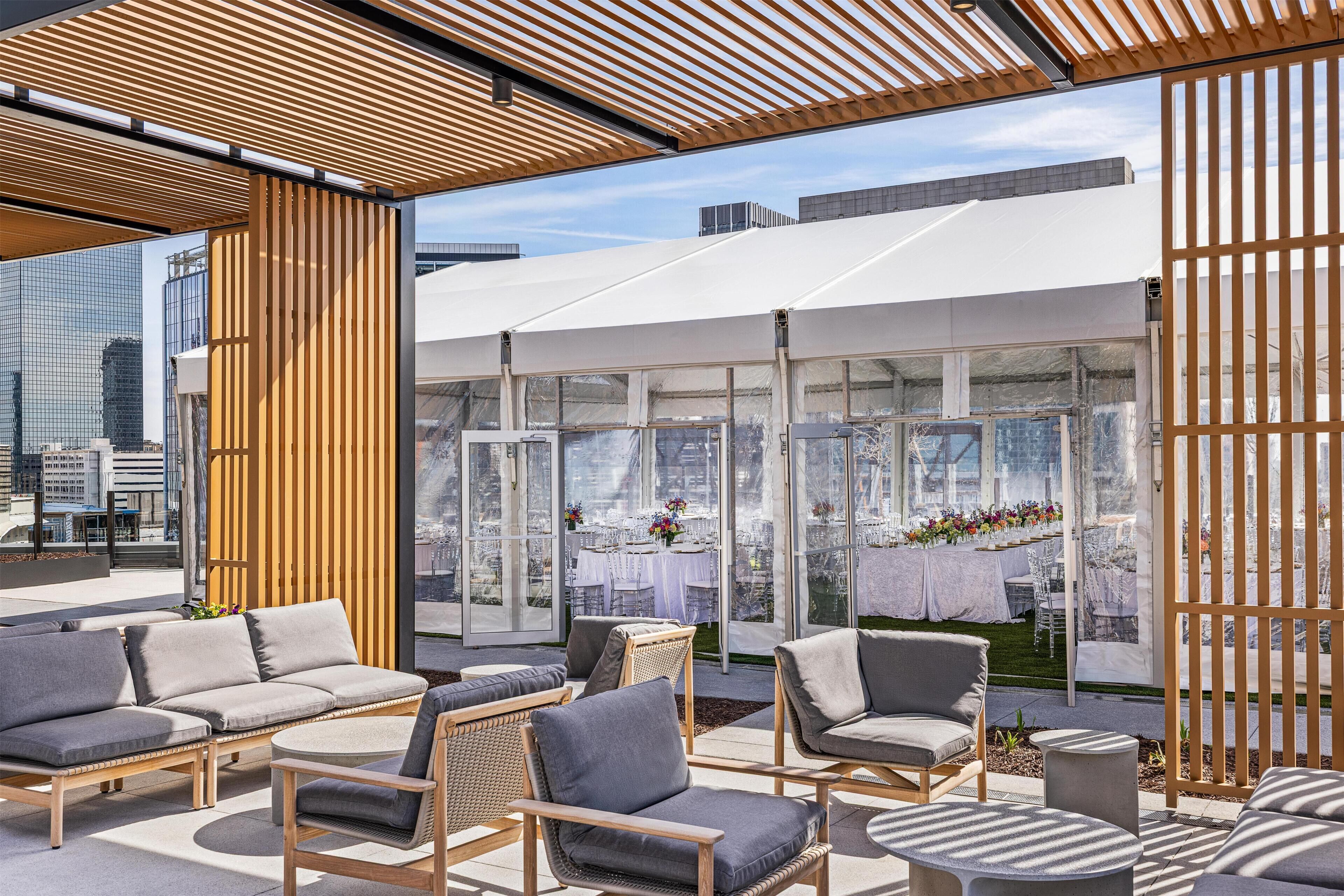 An outdoor seating area with modern furniture, a glass enclosure, and a city view.