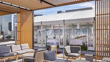 An outdoor seating area with modern furniture, a glass enclosure, and a city view.