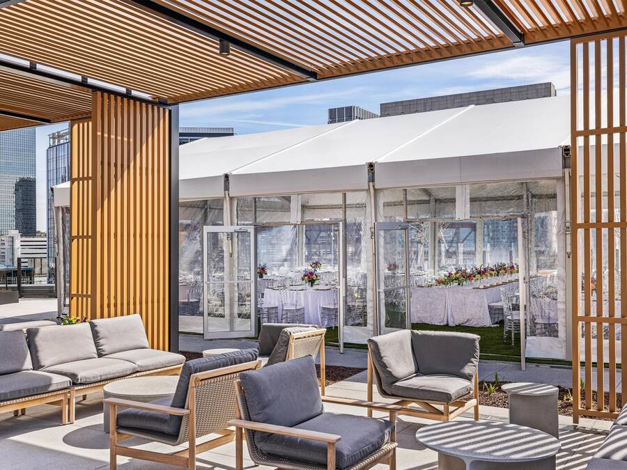 An outdoor seating area with modern furniture, a glass enclosure, and a city view.