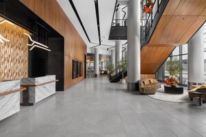 A spacious lobby with a reception desk, seating area, and a staircase.