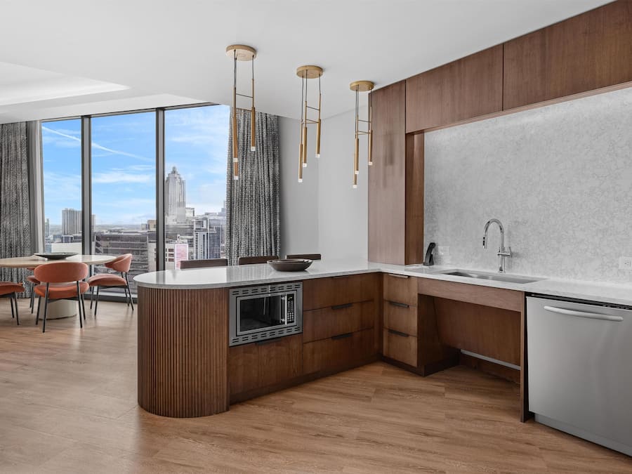 A modern kitchen with a built-in microwave, stainless steel dishwasher, and a large window offering a city view.