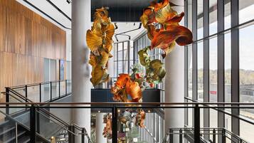 A modern interior with a central staircase, large windows, and hanging decorative elements.