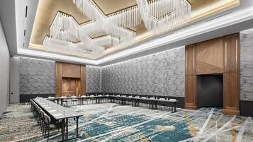 A conference room with a long table, white chairs, and a patterned carpet.