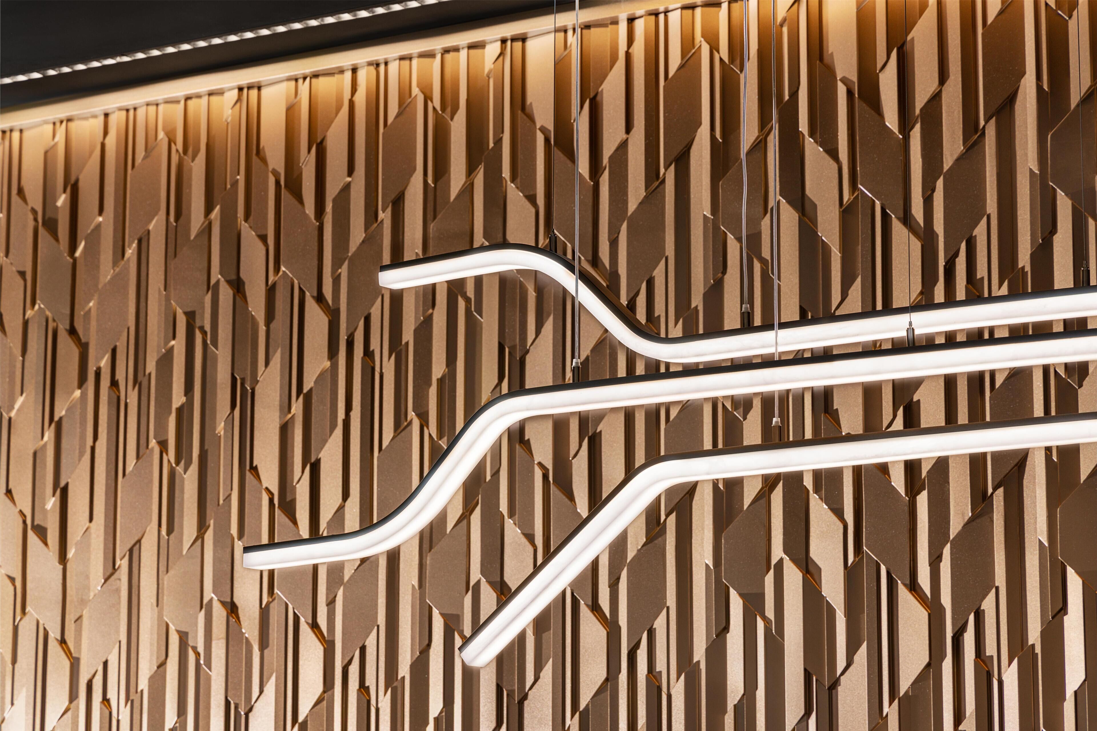 A modern wall with geometric patterns and two curved light fixtures.