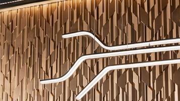 A modern wall with geometric patterns and two curved light fixtures.