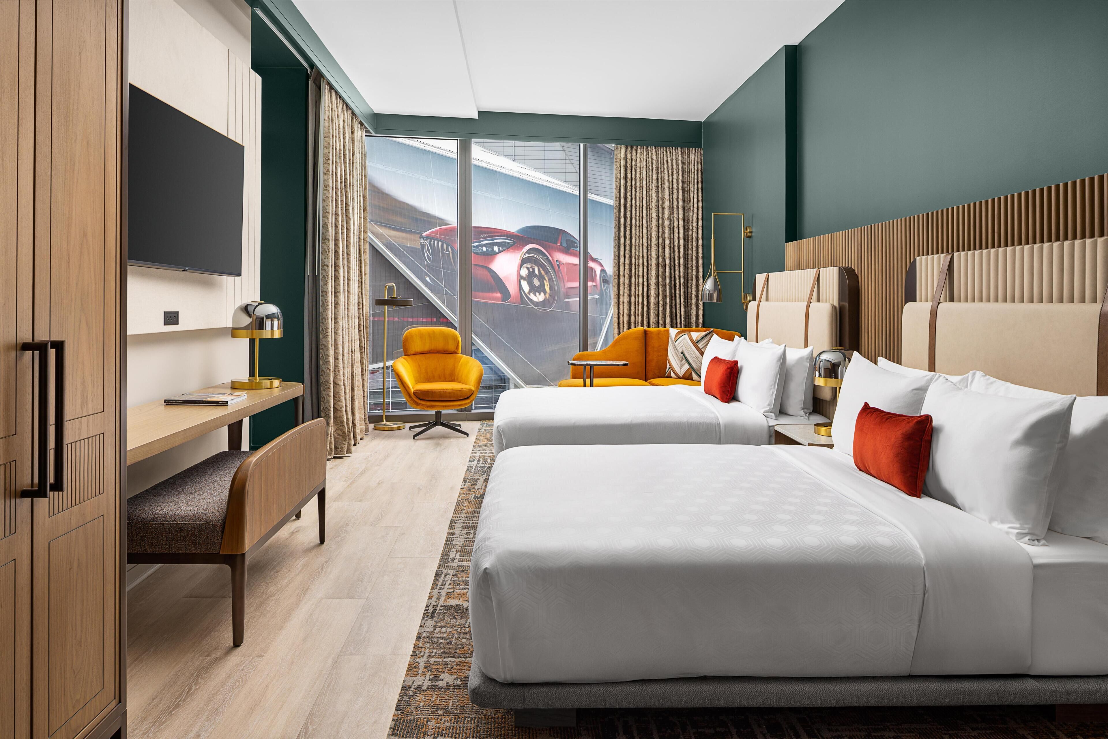 Ein Hotelzimmer mit einem großen Bett, einem Schreibtisch, einem Stuhl und einem Fernseher.