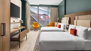 Ein Hotelzimmer mit einem großen Bett, einem Schreibtisch, einem Stuhl und einem Fernseher.