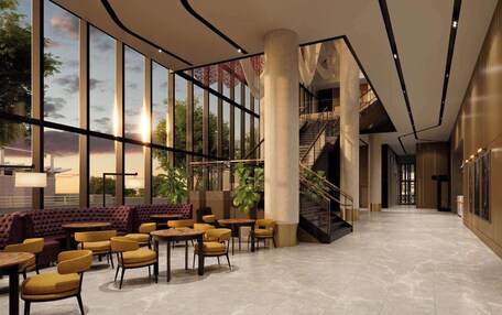A spacious indoor area with large windows, a staircase, and seating arrangements.