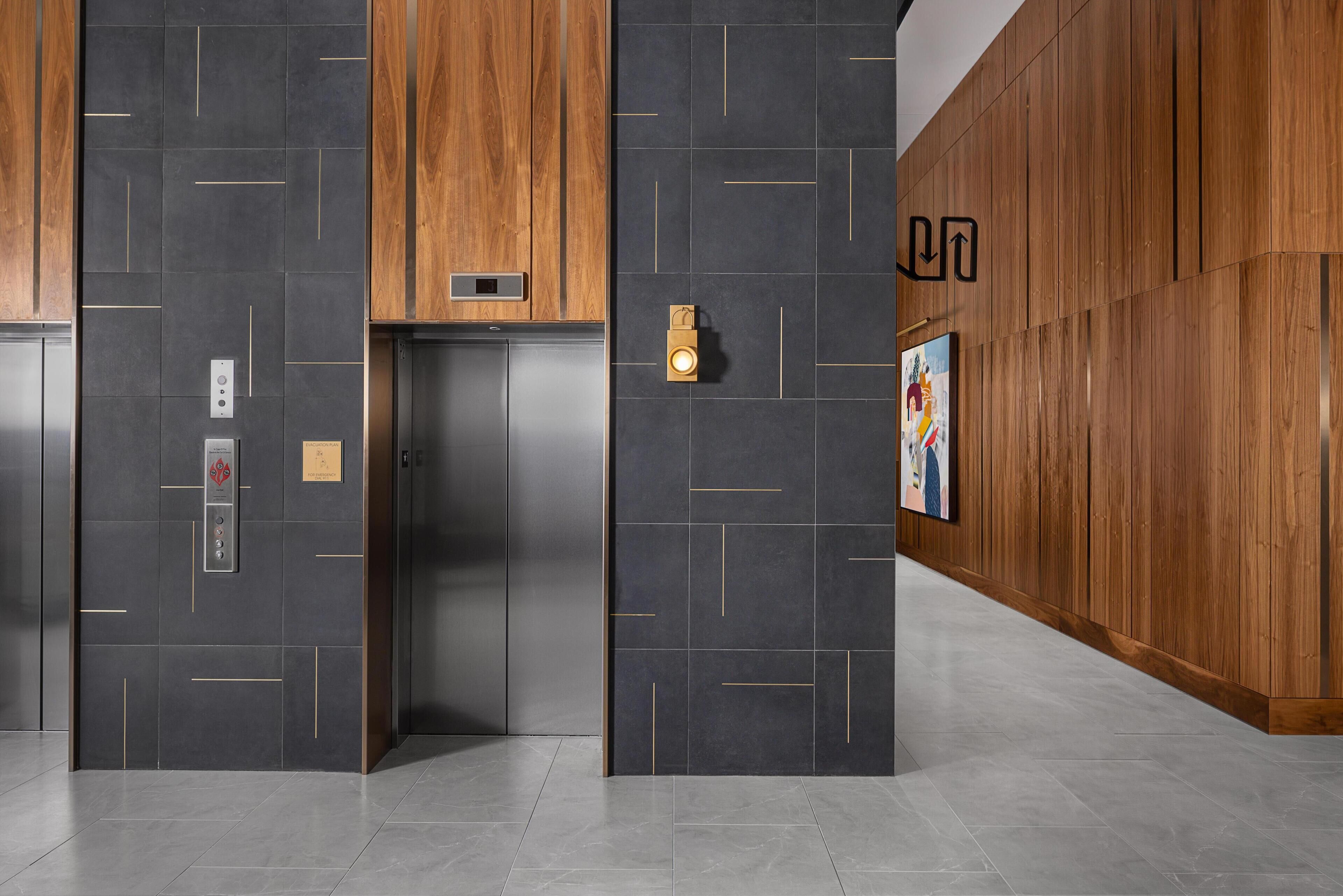 An elevator with a modern design, a wall-mounted light, and a directional sign.
