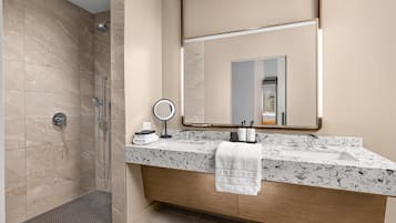 Une salle de bain moderne équipée d’une douche, d’un meuble-lavabo avec un plan de travail en marbre, d’un grand miroir et d’une serviette accrochée au mur.