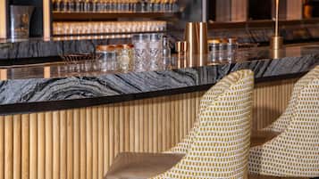 Eine Bar mit Marmorplatte, gepolsterten Sitzgelegenheiten und einer Holzvertäfelung.
