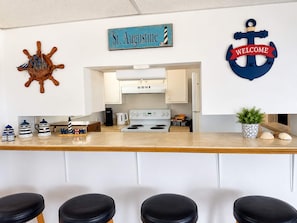 A kitchen with a sign reading 'St. Augustine,' a welcome anchor decoration, and a coffee bar area. - Butler Beach Oasis - Steps To Beach - Pets Welcome (St. Augustine)