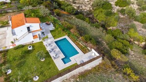 Une vue aérienne d’une maison avec une piscine, entourée de verdure et d’un paysage vallonné.