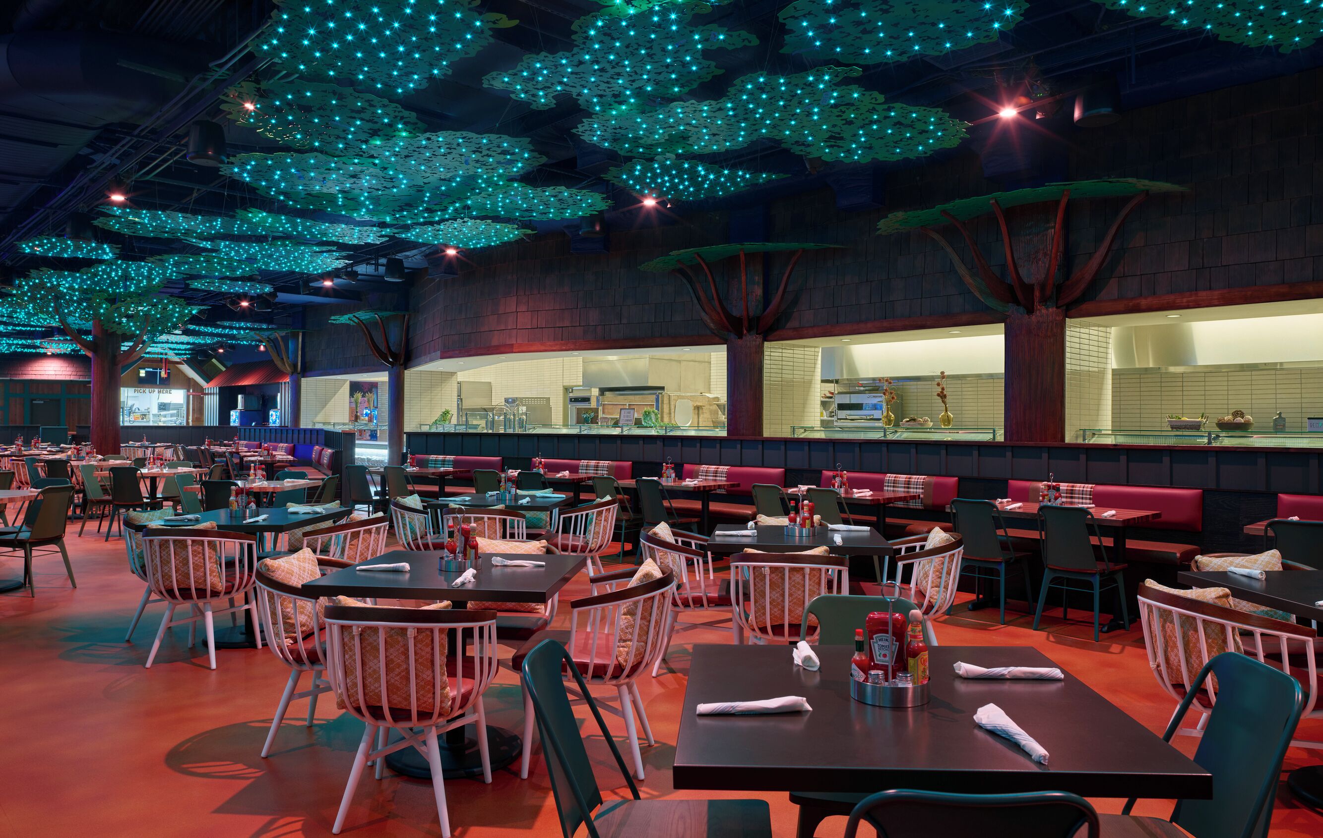 Un restaurant doté de nombreuses tables et chaises, d’un comptoir avec un présentoir, et d’un plafond orné de luminaires suspendus.