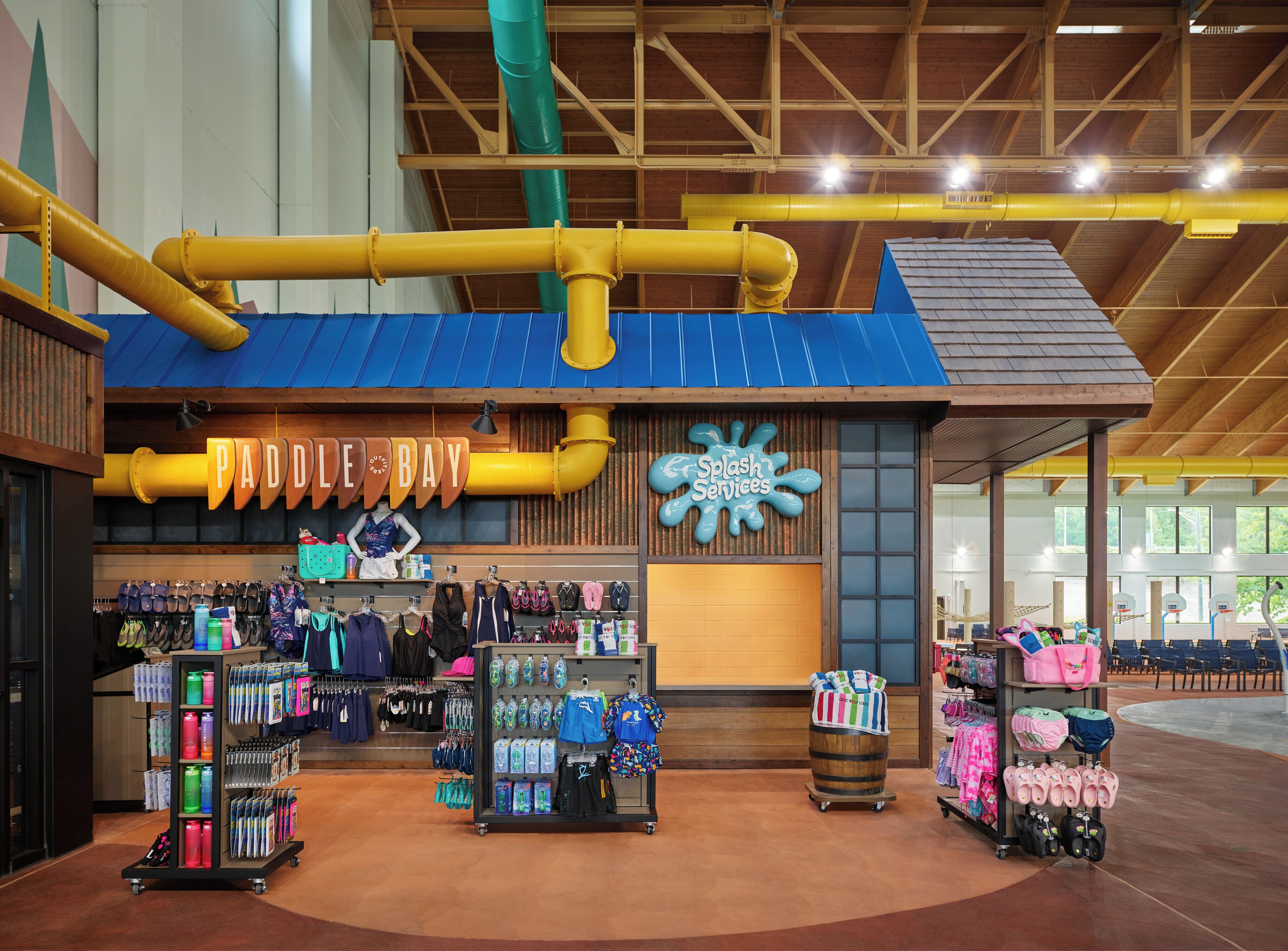 A retail store with a blue roof and yellow pipes, featuring a 'Paddle Bay' sign and 'Splash Services' sign.
