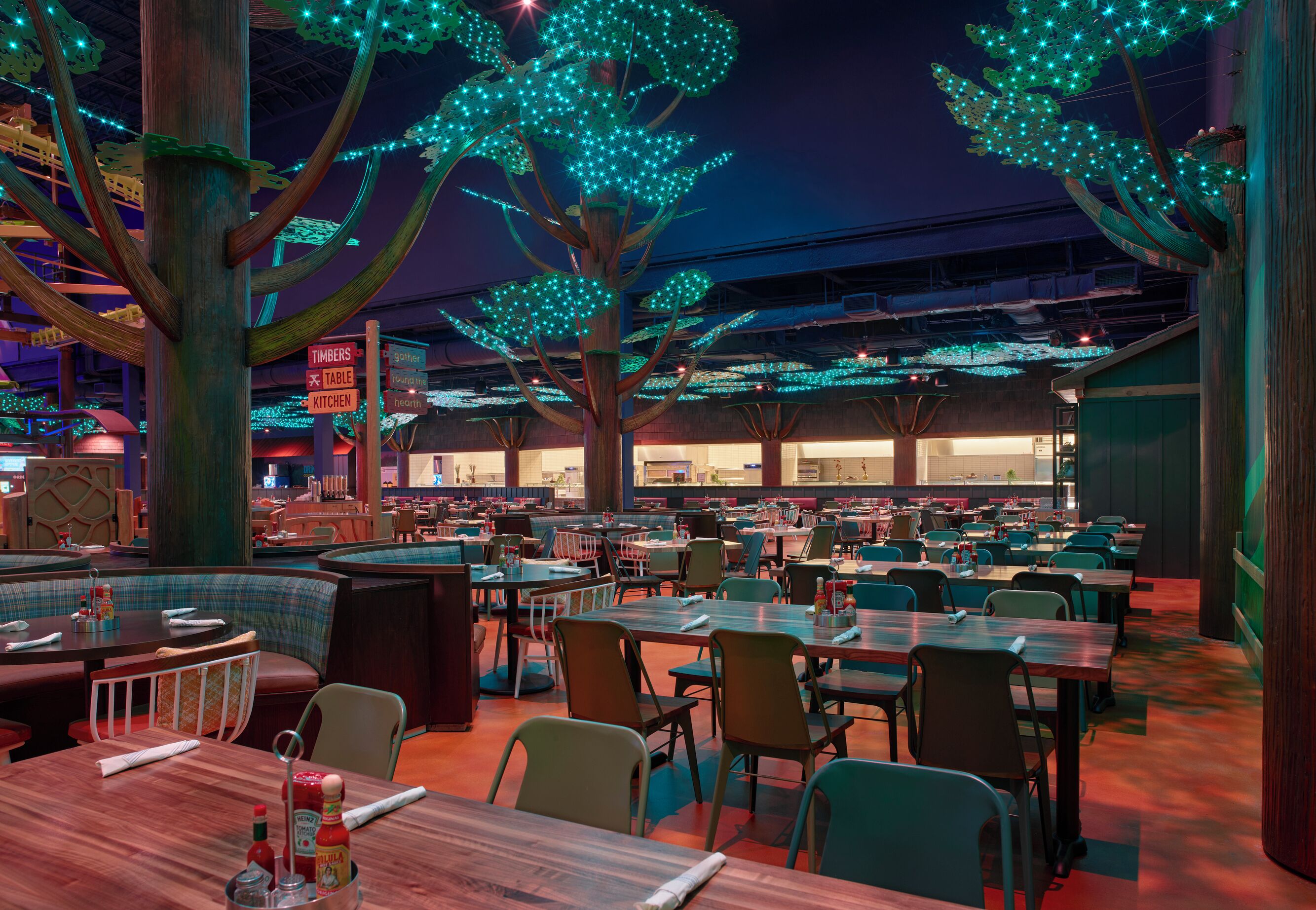 A restaurant with booths and tables, illuminated by blue lights on trees.