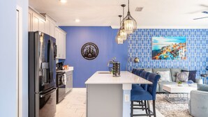 Een moderne keuken met een centraal kookeiland, roestvrijstalen apparatuur en een blauwe accentmuur.