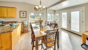 A spacious kitchen with wooden cabinets, a marble countertop, and a dining area with a wooden table and chairs. - Walk to Marina: Harrison Cabin w/ Lake View! (Harrison)