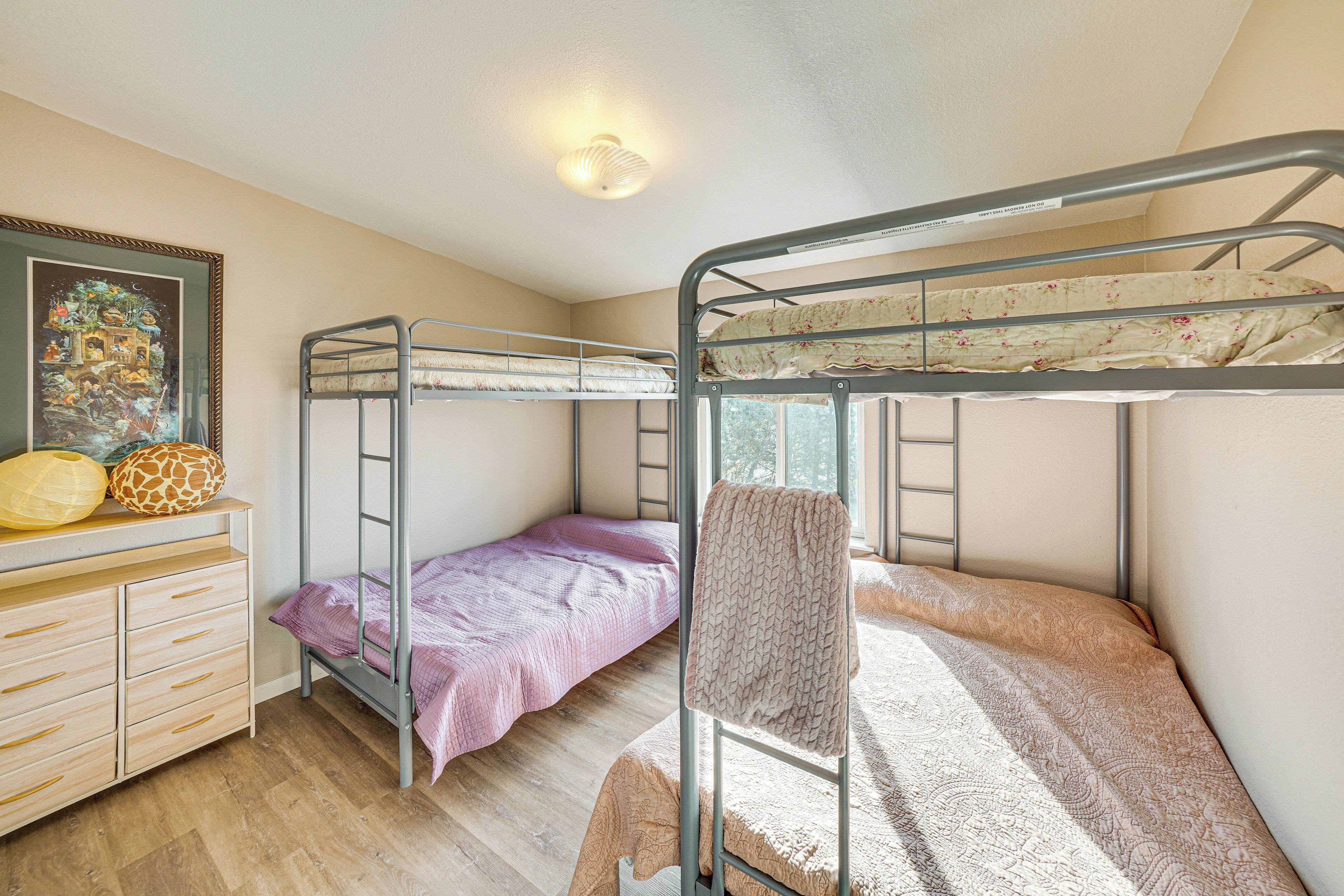 A bunk bed room with a wooden dresser and a framed picture on the wall.