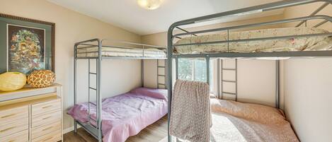 A bunk bed room with a wooden dresser and a framed picture on the wall.