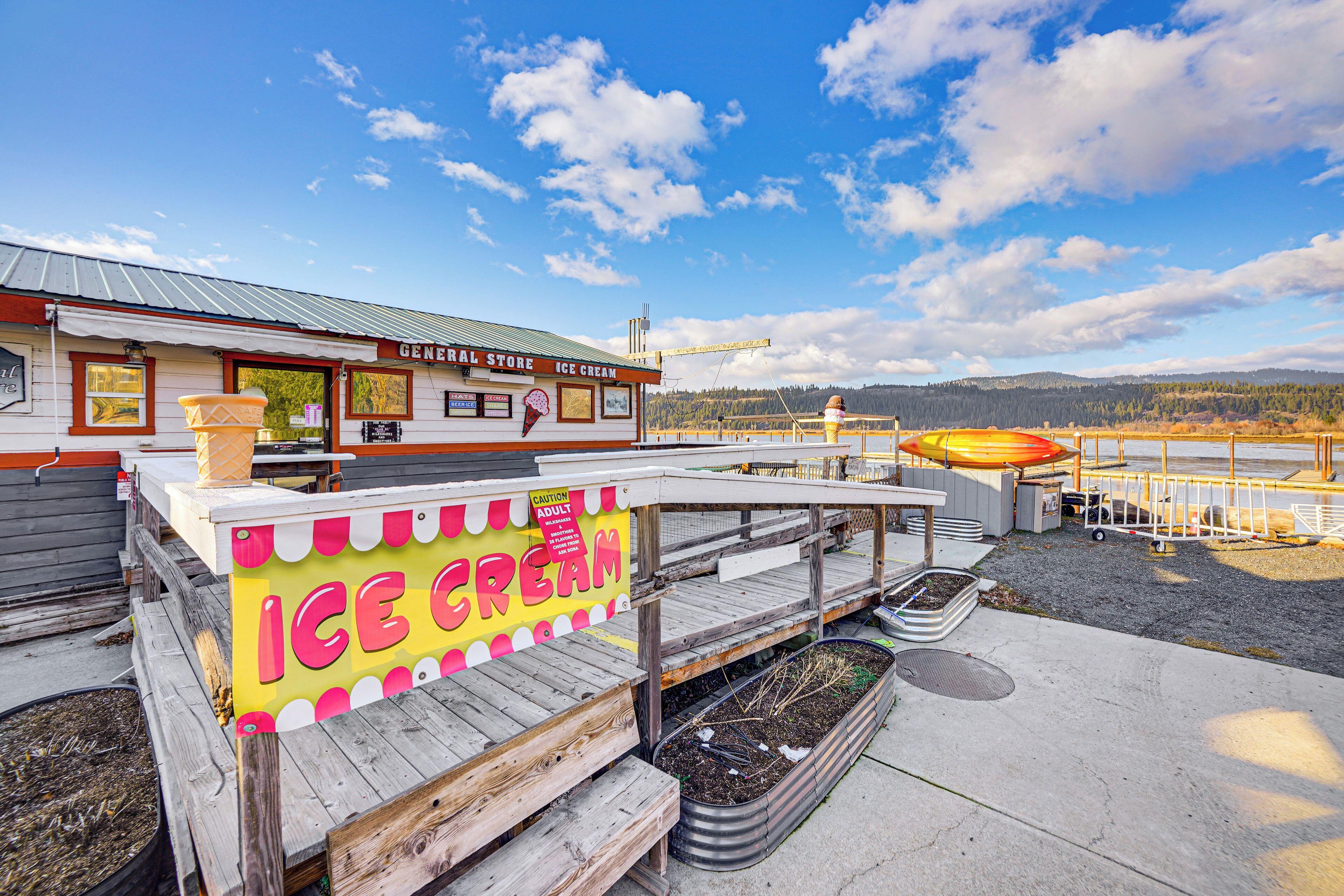 An ice cream shop with a wooden deck and a view of a lake and mountains in the background.